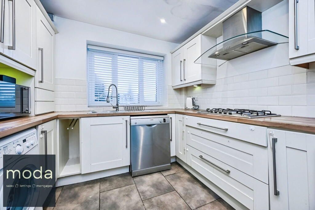Cream kitchen with stainless steel appliances, sink under a window, and gas stove.