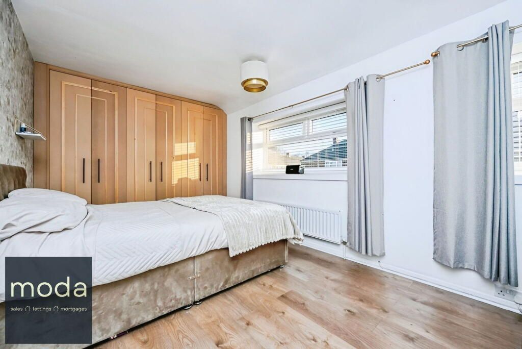Bedroom with wooden floor, built-in closet, double bed, and window with curtains.
