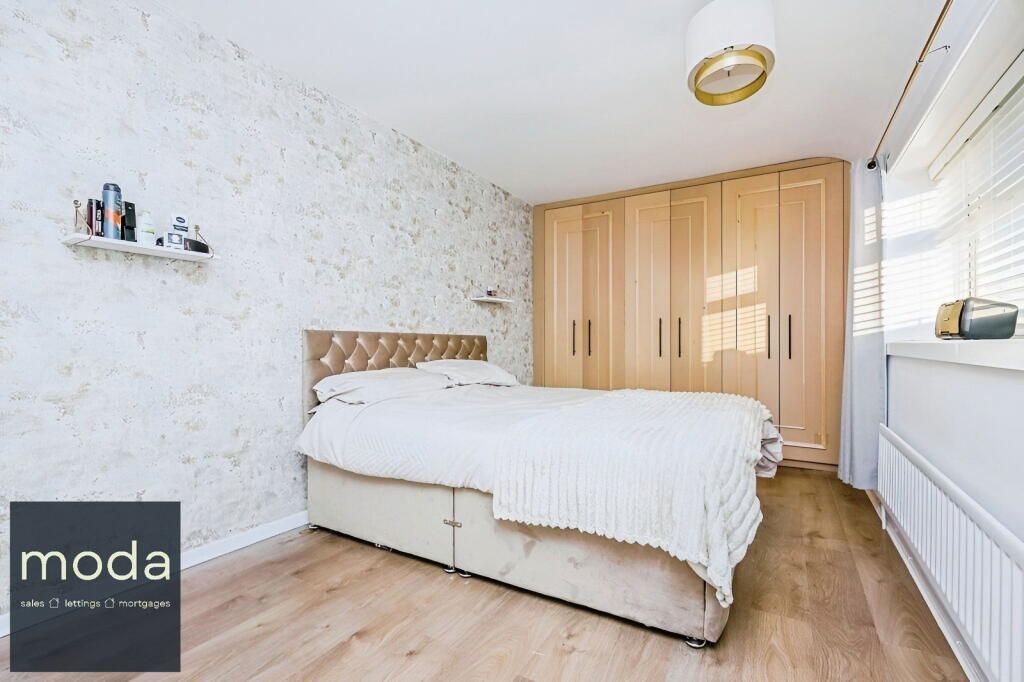Bedroom with double bed, built-in wardrobe, and light-colored textured wallpaper.