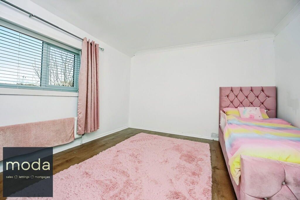 Pink bedroom with a rug, bed, and curtains.