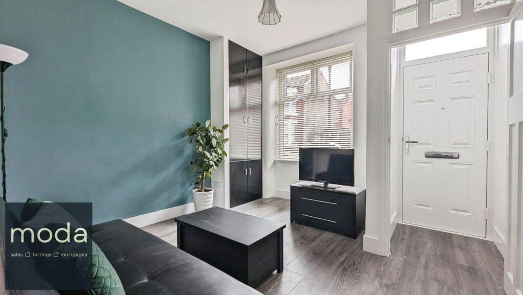 Living room with teal wall, black furniture, and front door open.