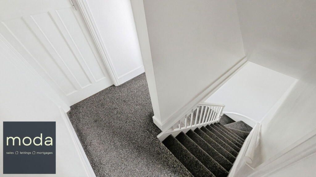 Overhead view of a carpeted staircase with white walls and a door to the left.