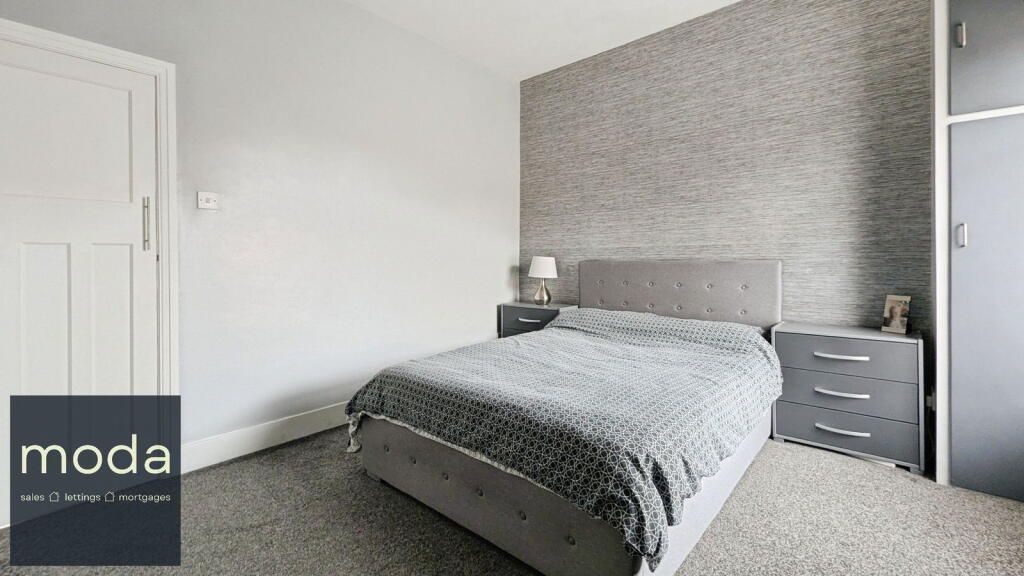 Bedroom with gray walls, bed, carpet and bedside tables.