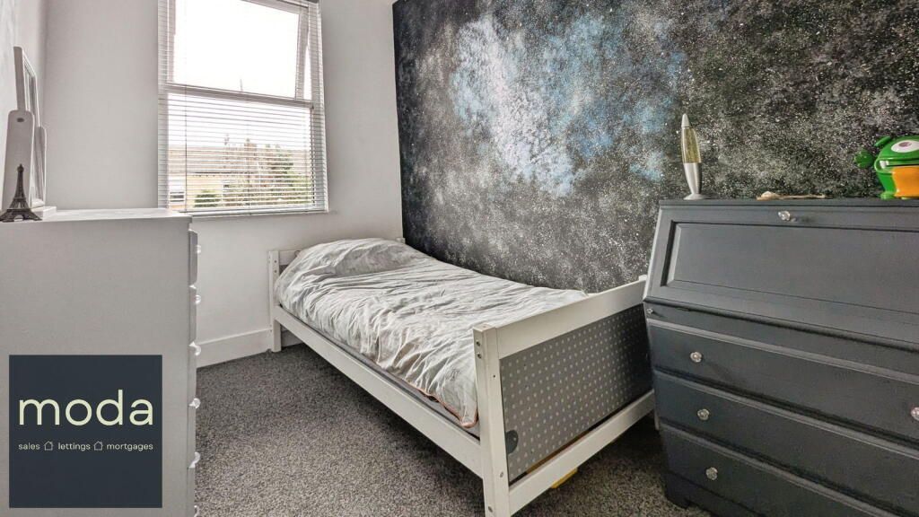 Bedroom with single bed against wall with galaxy mural, window, and dark dresser.