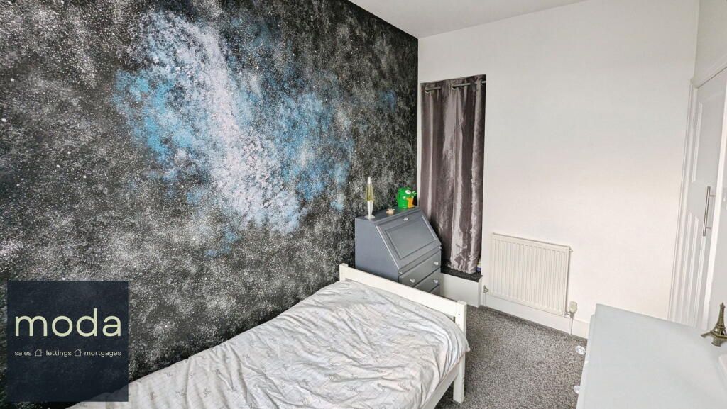 Bedroom with galaxy-print wall, twin bed, dresser, curtains, and radiator.