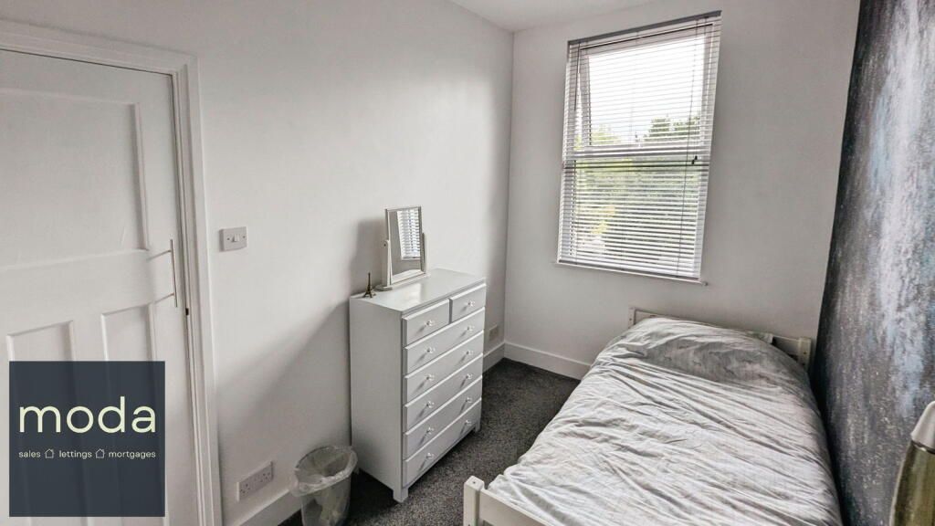 Small bedroom with a single bed, dresser, window, and white door.