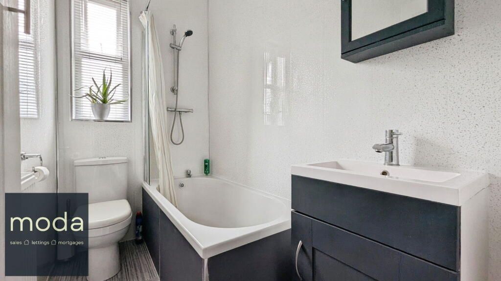 Small bathroom with a white bathtub, toilet, and vanity; the walls are white.