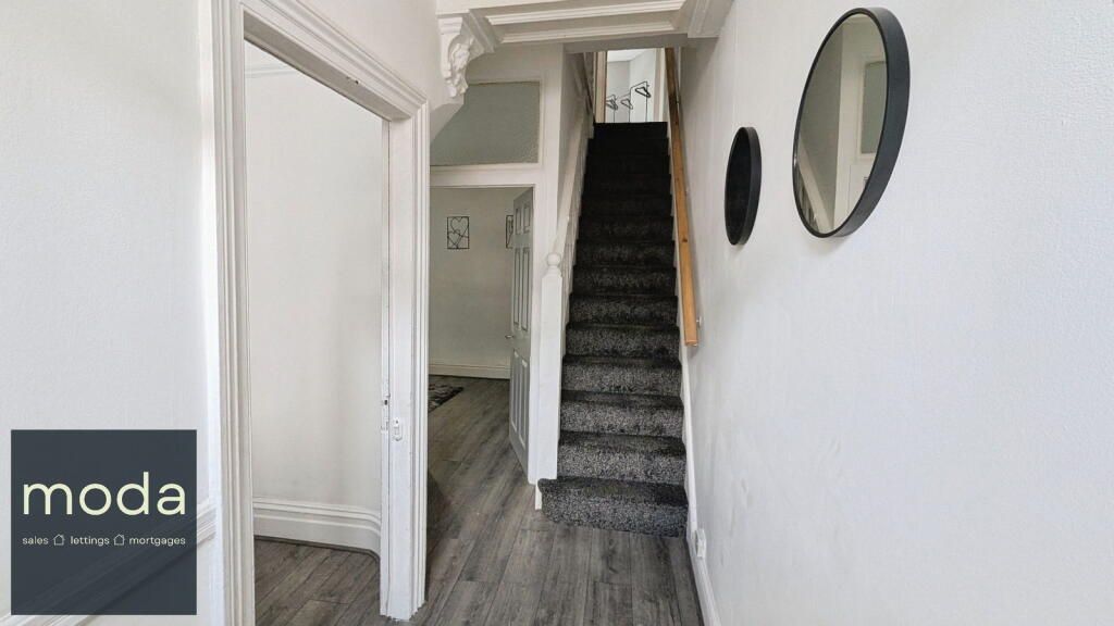 Narrow hallway with stairs, leading to an upper floor, with mirrors on the wall.