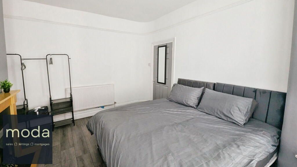 Bedroom with gray bedding, a bed with a tufted headboard, and a standing screen.