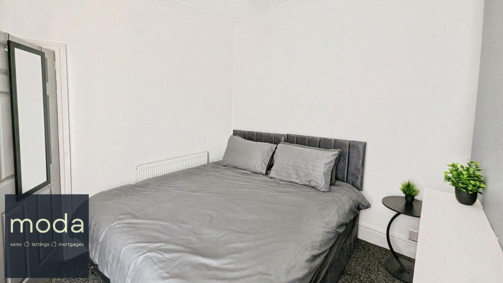 Gray bedroom with a bed, side table, and a small plant.