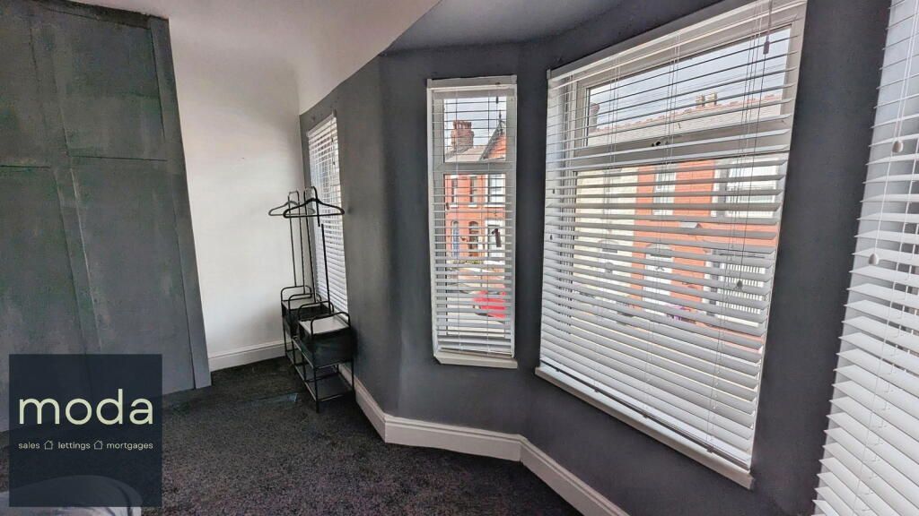 Room with dark gray walls, white blinds, and a clothes rack.