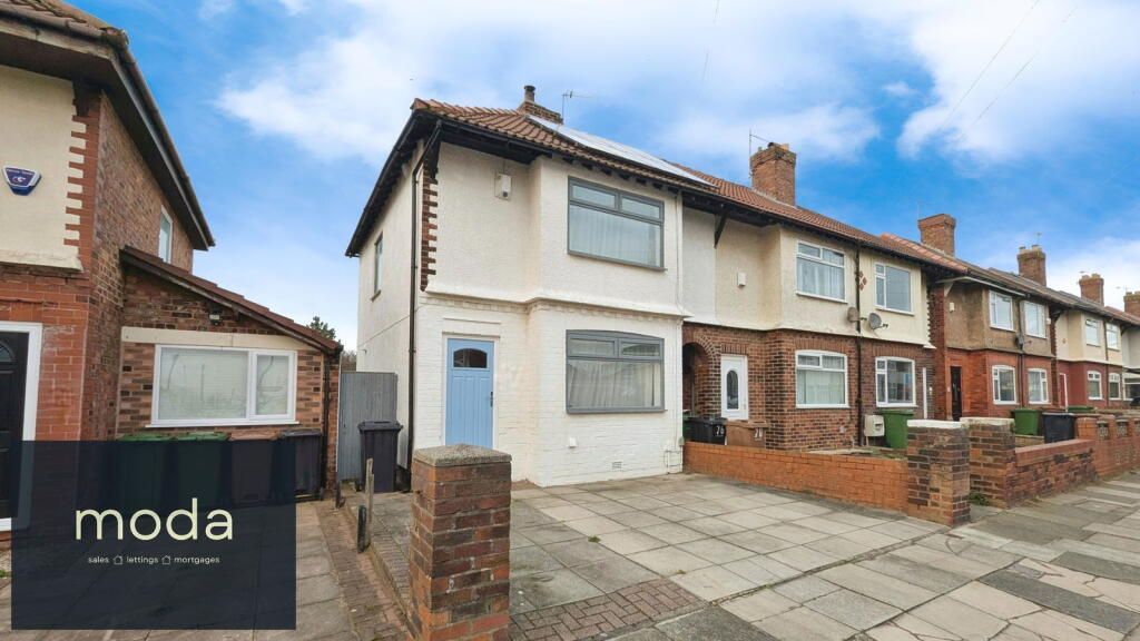 Row of terraced houses, light blue door on one, grey driveway, cloudy sky.