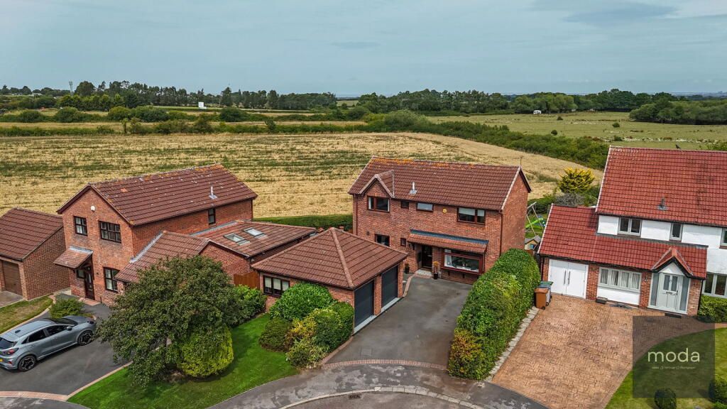 Houses with red roofs and a view of a field on a cloudy day.