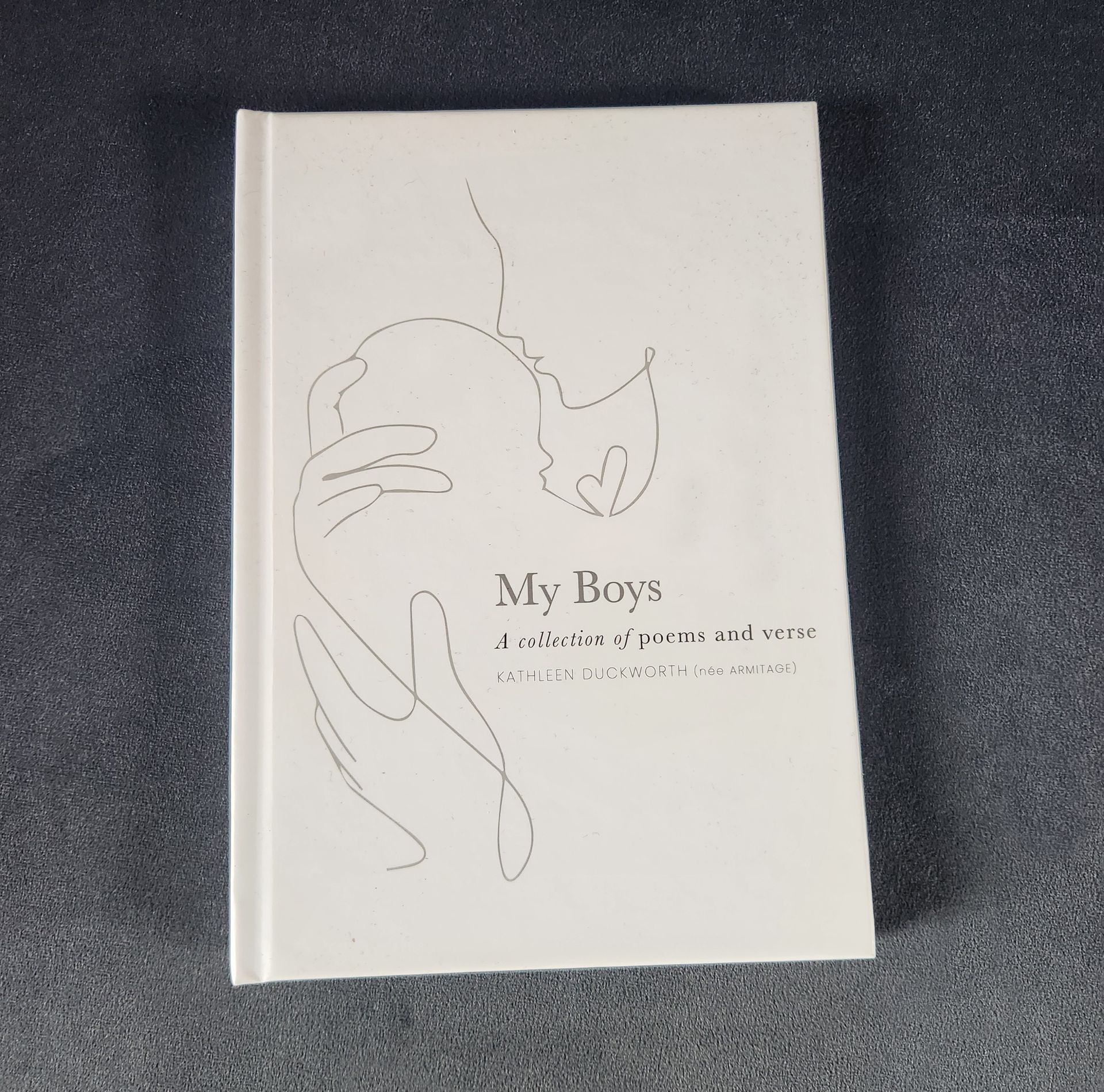 White book cover with minimalist line art and the title “My Boys” on a dark fabric background
