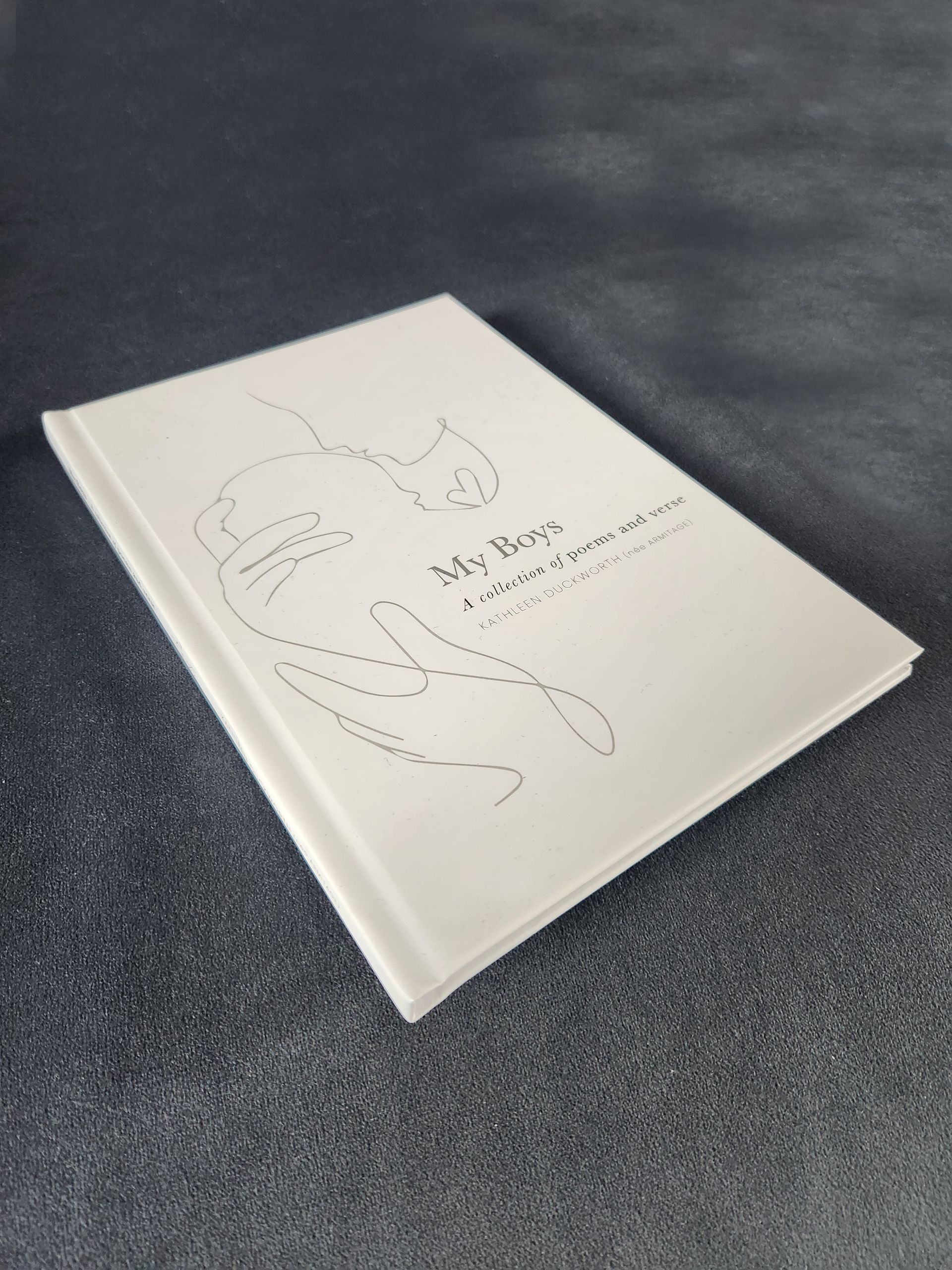 White notebook with a minimalist line drawing on the cover, resting on a dark textured surface.