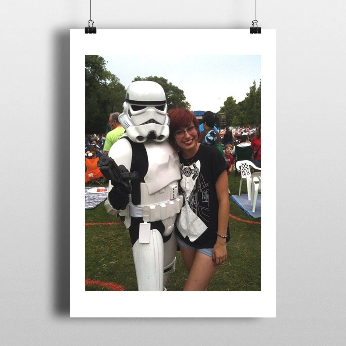 Person posing with a Stormtrooper at an outdoor event, both smiling and standing on grass.