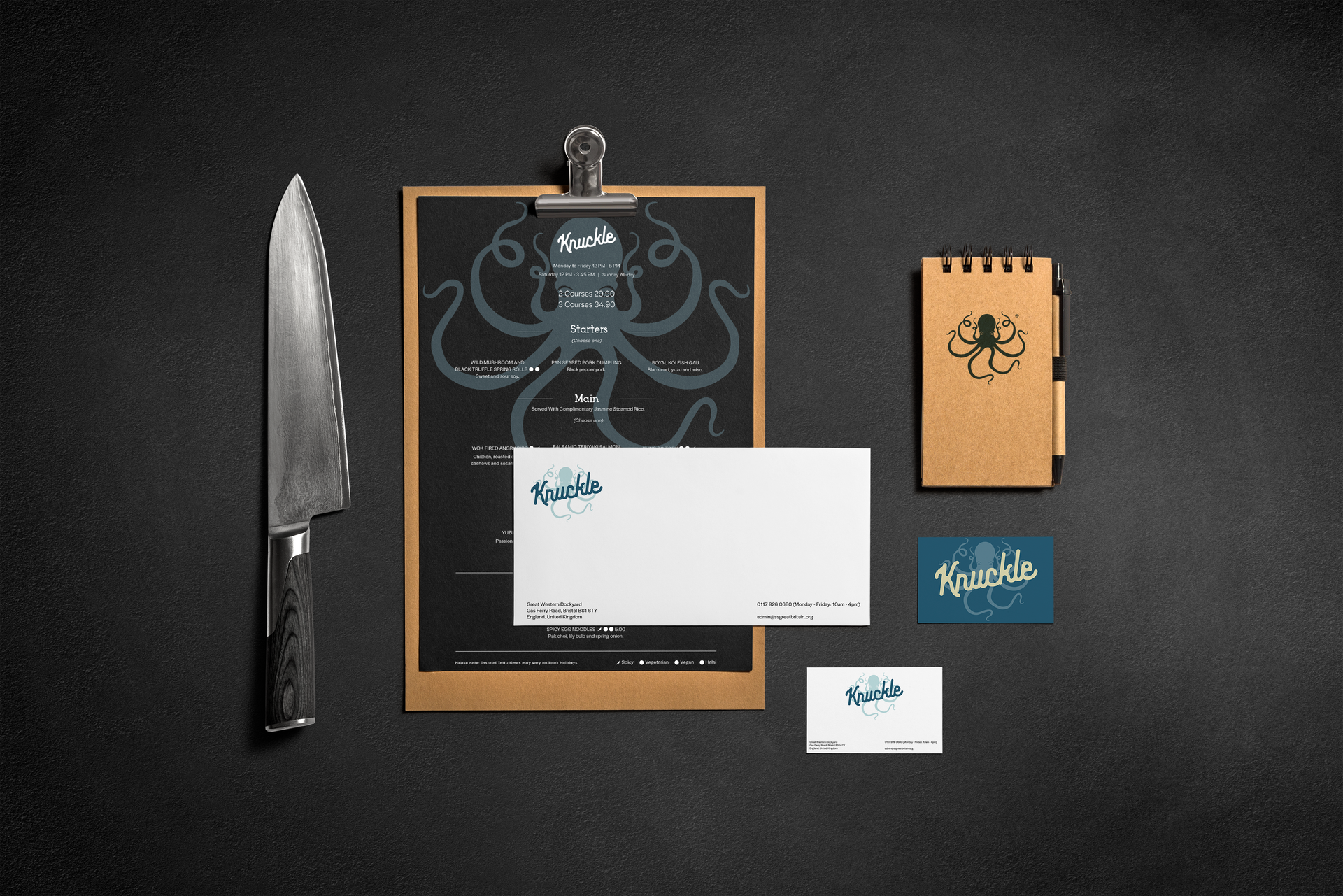 Knife beside a black notebook and cards on a dark background