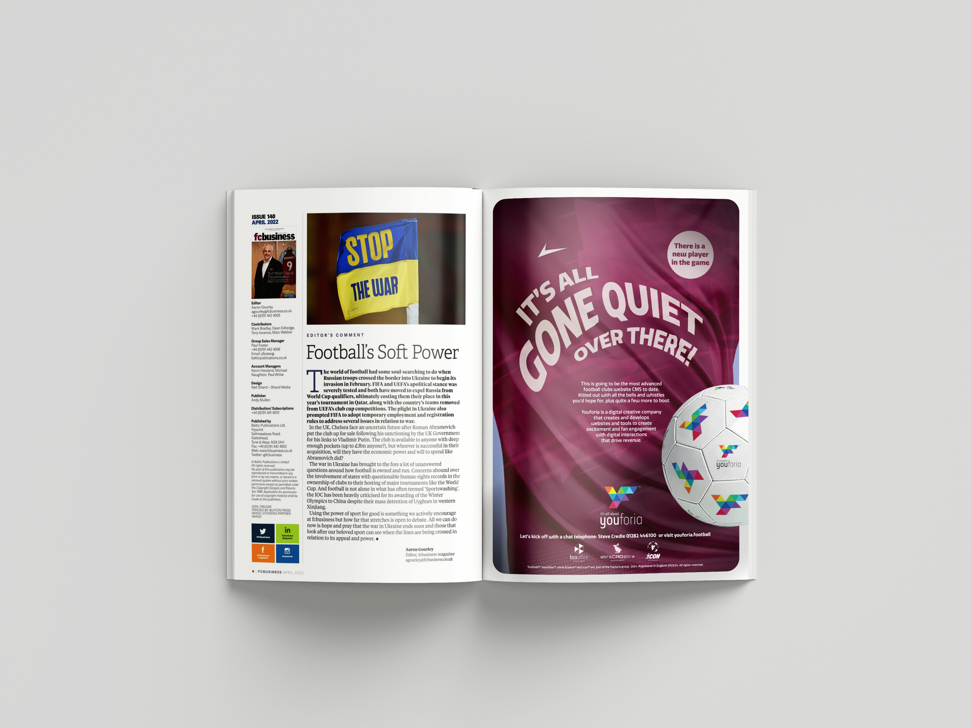Open magazine spread with text on the left page and a purple ad on the right reading “It’s all gone quiet on the front”