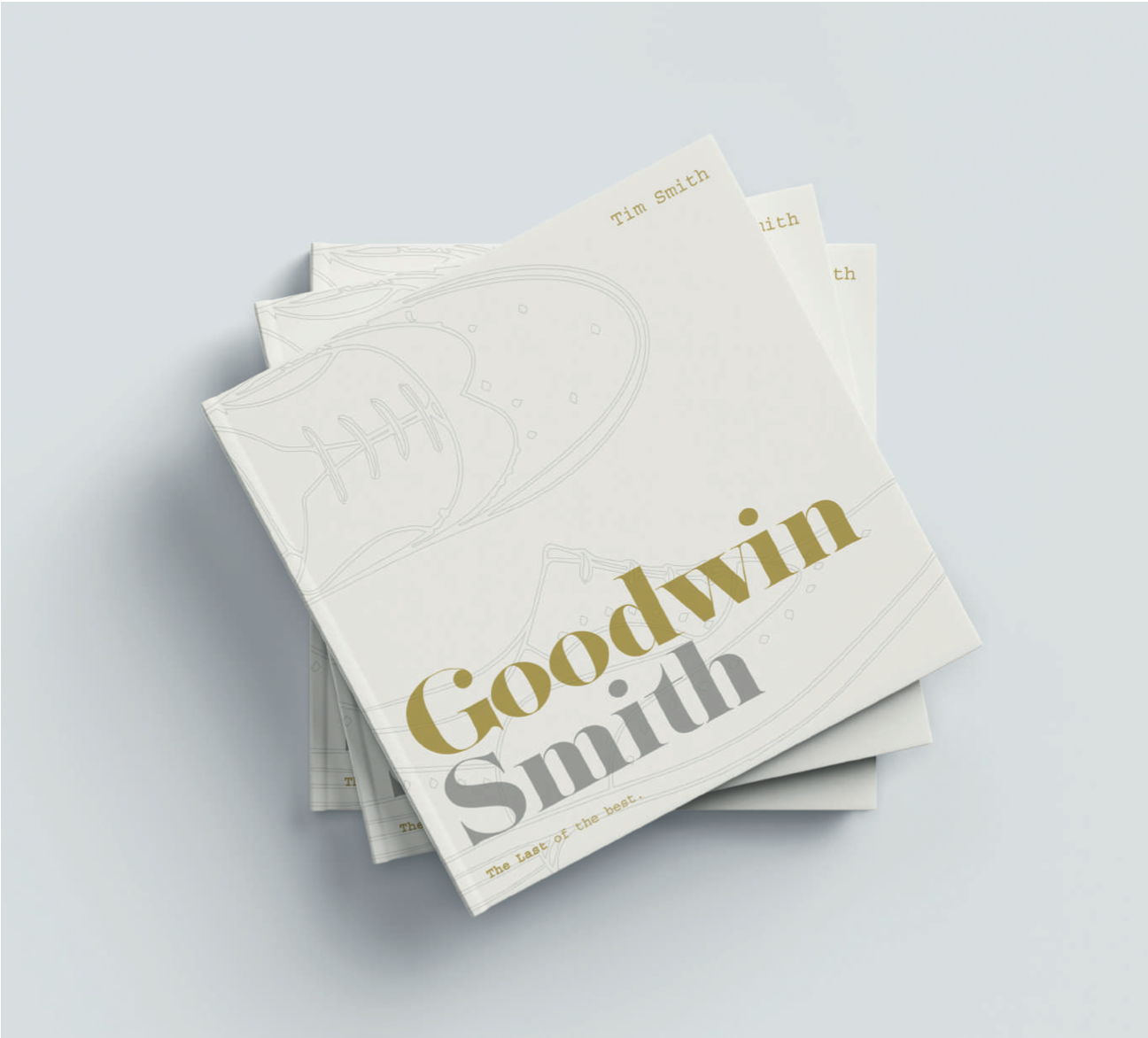 Stack of minimalist white business cards with gold “Goodwin Smith” text on a light gray background
