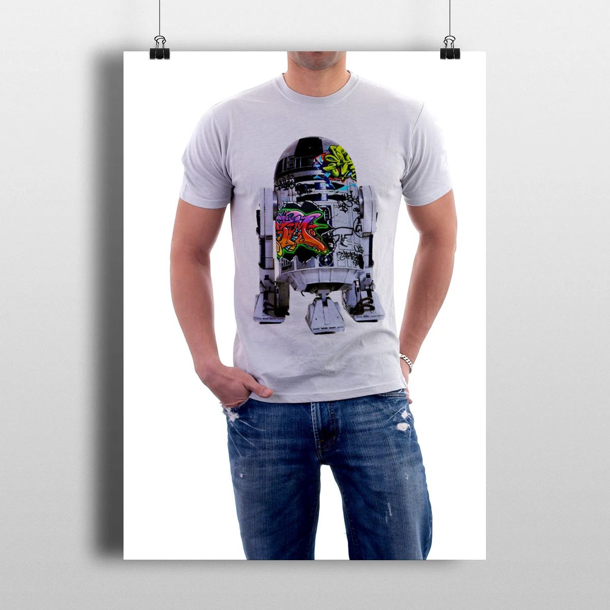 Man wearing a light gray graphic T-shirt with a colorful robot design and blue jeans on a white background