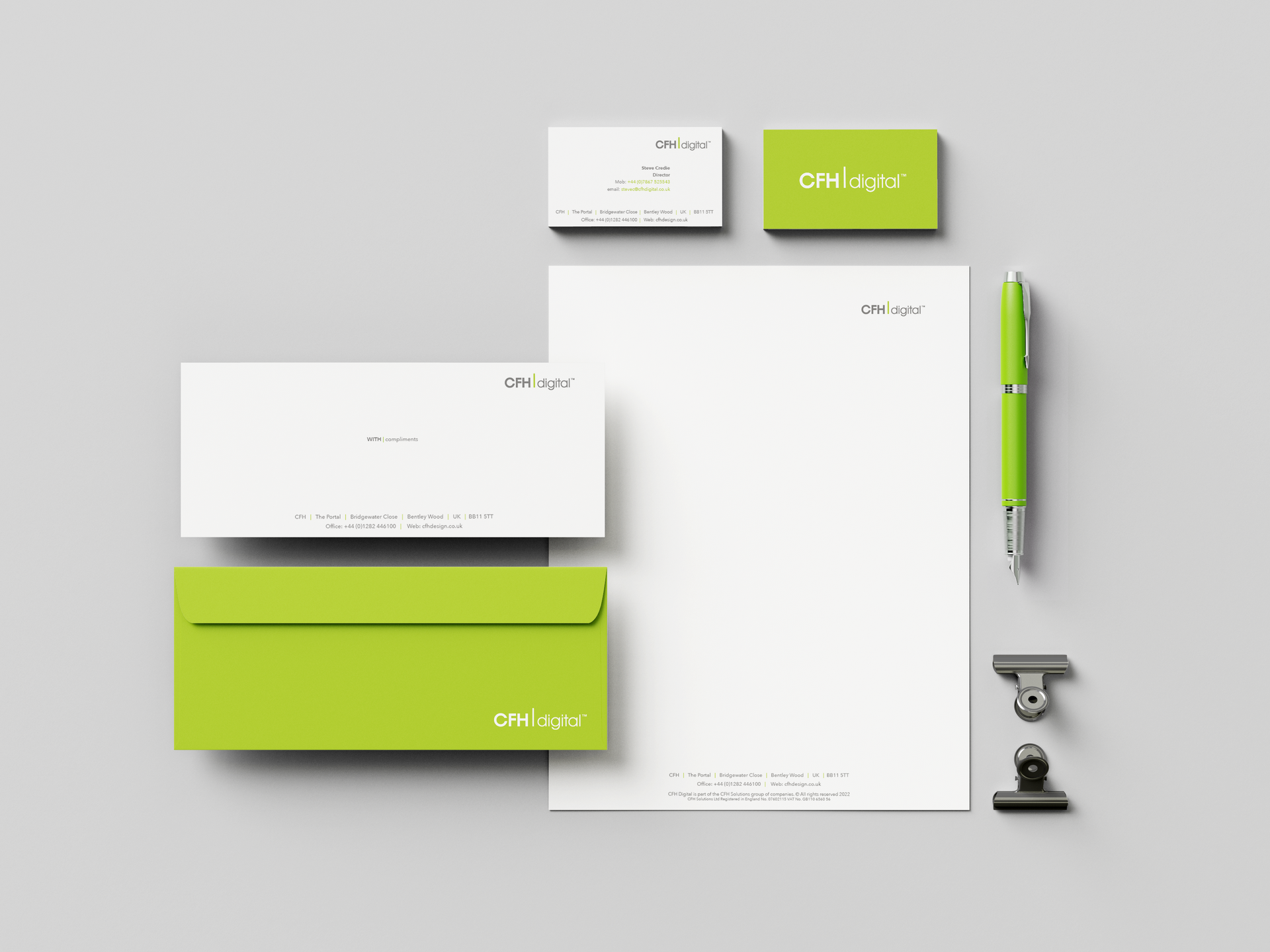 White and lime-green stationery set with cards, notebook, pen, and clips on a gray background