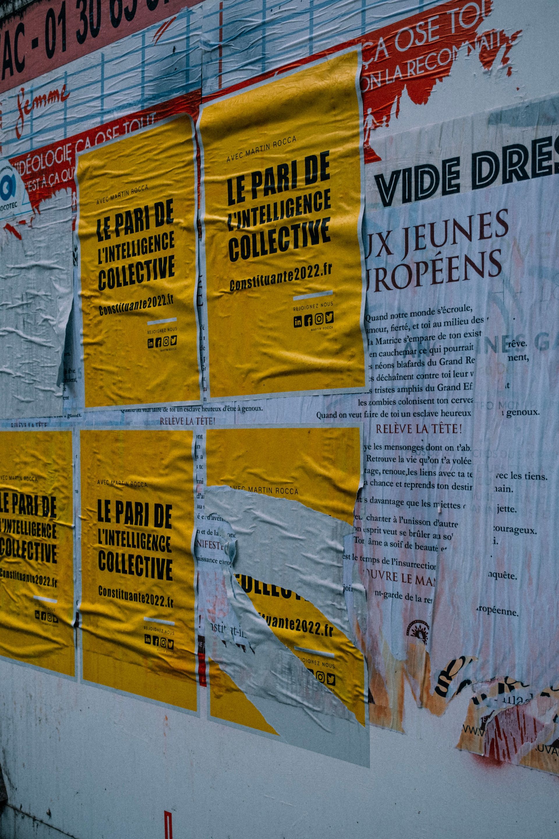 Yellow event posters pasted on a wall, including one for “Vive Dre…” and “Le Palais de…”