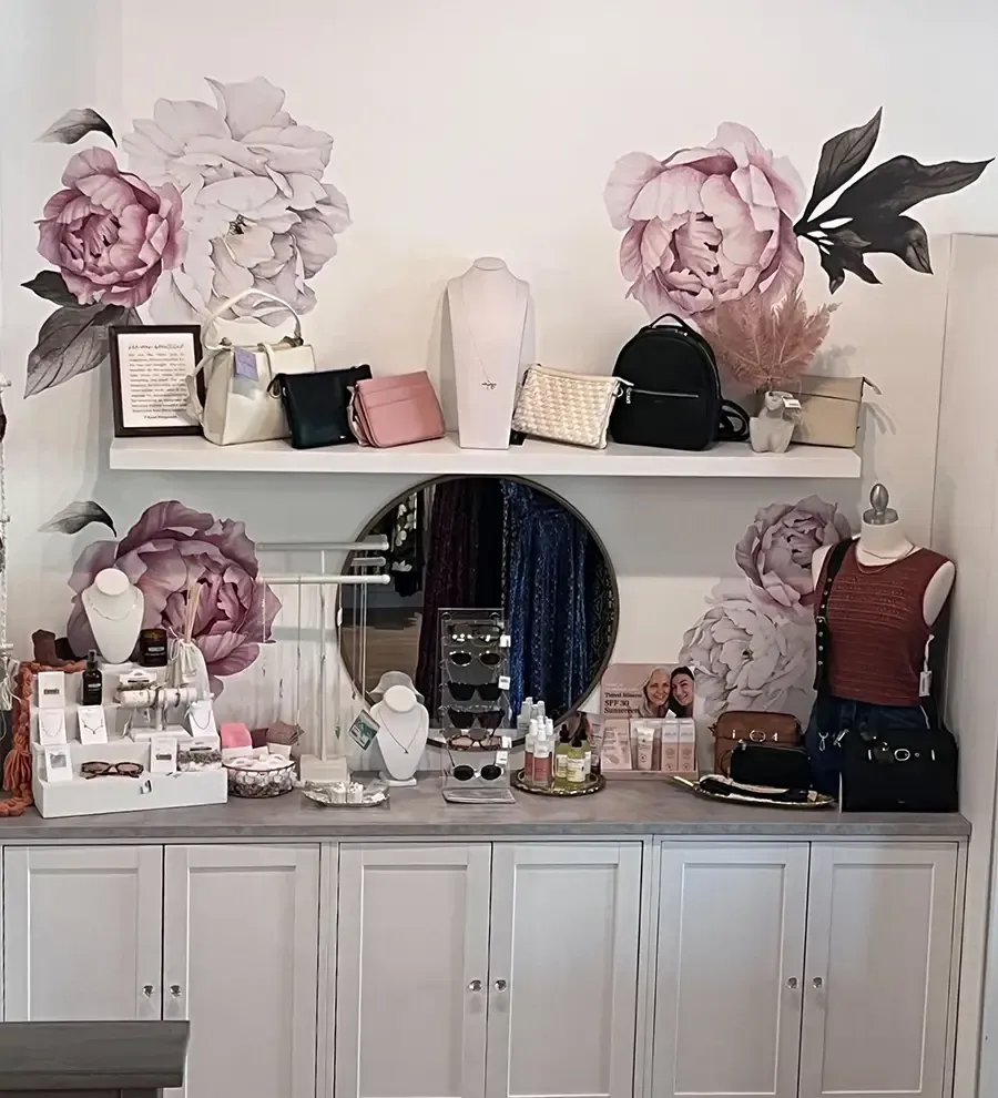 Decorative dresser display with floral wall art, hats, jewelry, and mannequins in a bedroom or boutique setting
