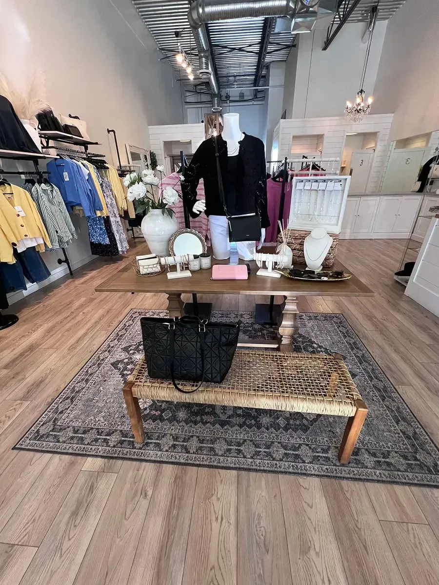 Clothing boutique interior with racks of apparel, display tables, and wood flooring