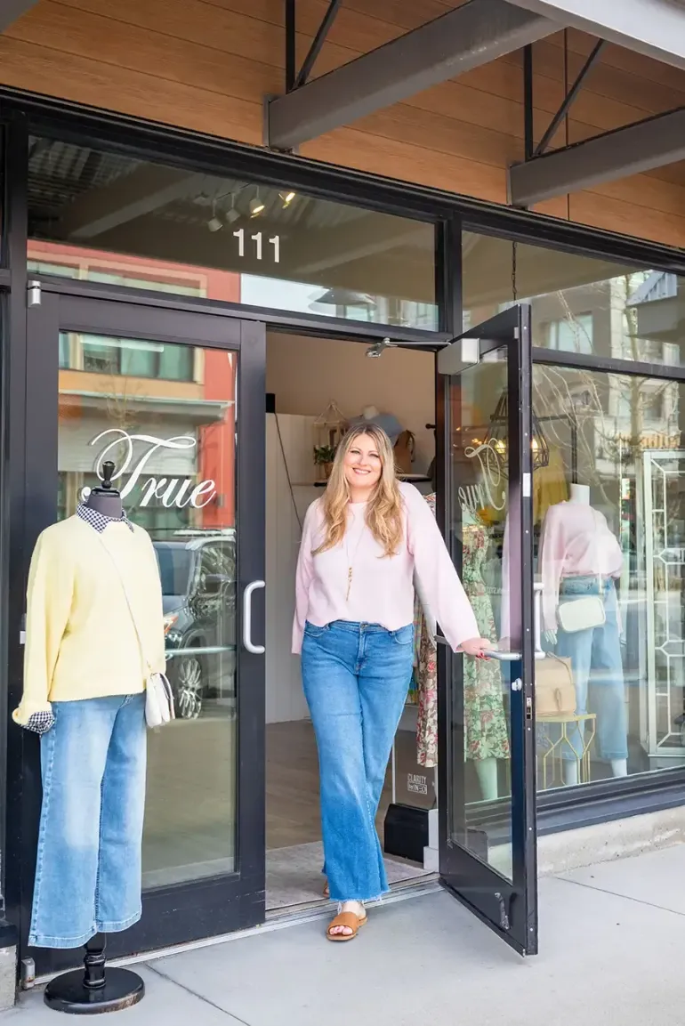 Woman stepping out of a boutique storefront with mannequins in the window