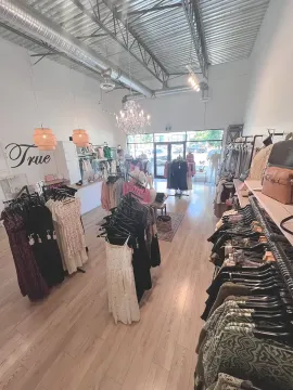 Clothing boutique with dresses on racks, mannequins, and a bright front entrance.