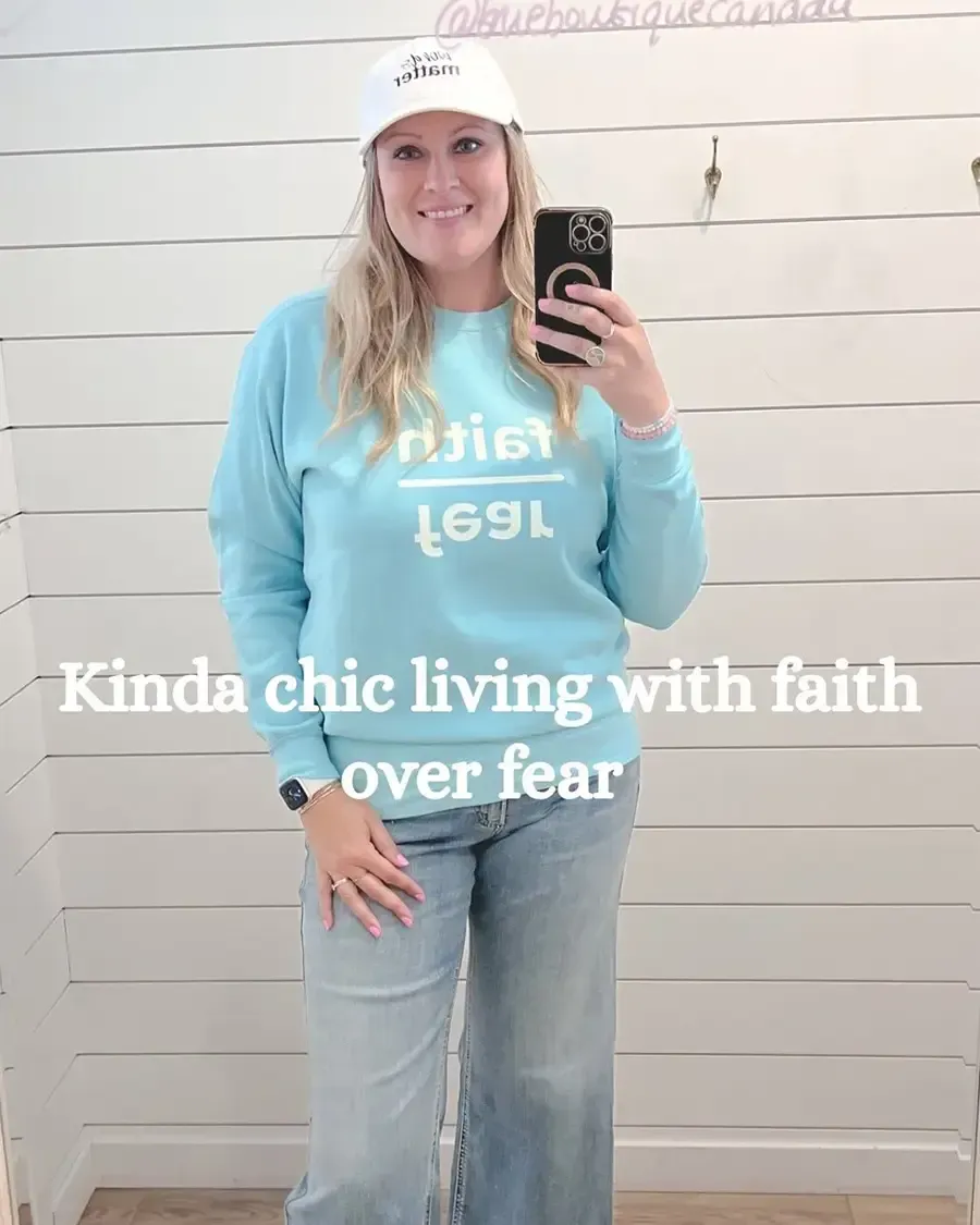 Woman taking a mirror selfie in a light blue outfit and white cap, with text reading “Kinda chic living with faith over fear”
