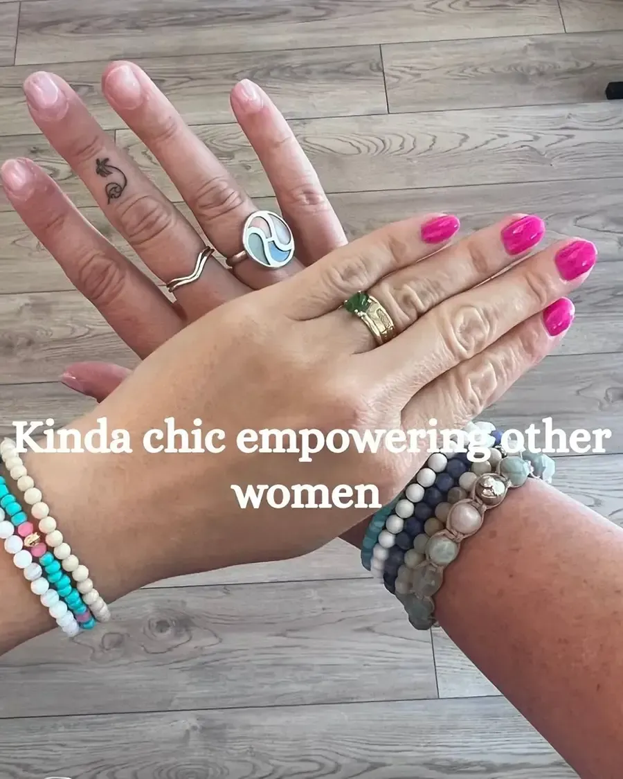 Stacked hands with colorful bracelets and rings, overlaid text reads “Kinda chic empowering other women”