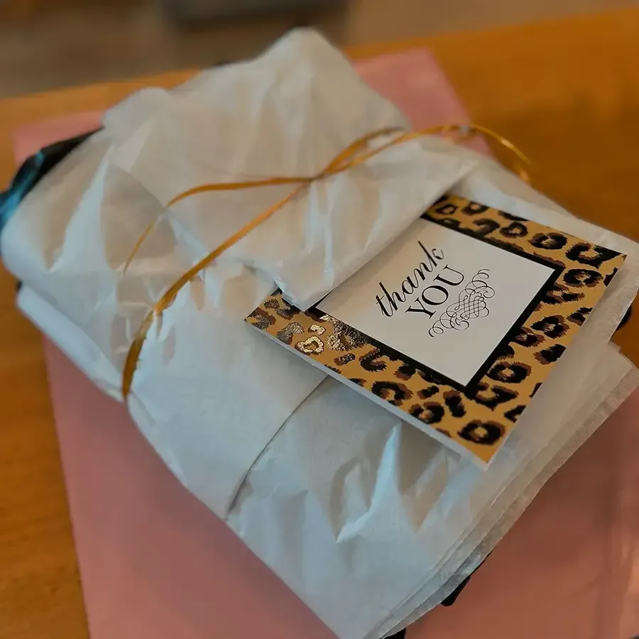 Wrapped gift with a “thank you” tag and leopard-print border on a pink surface