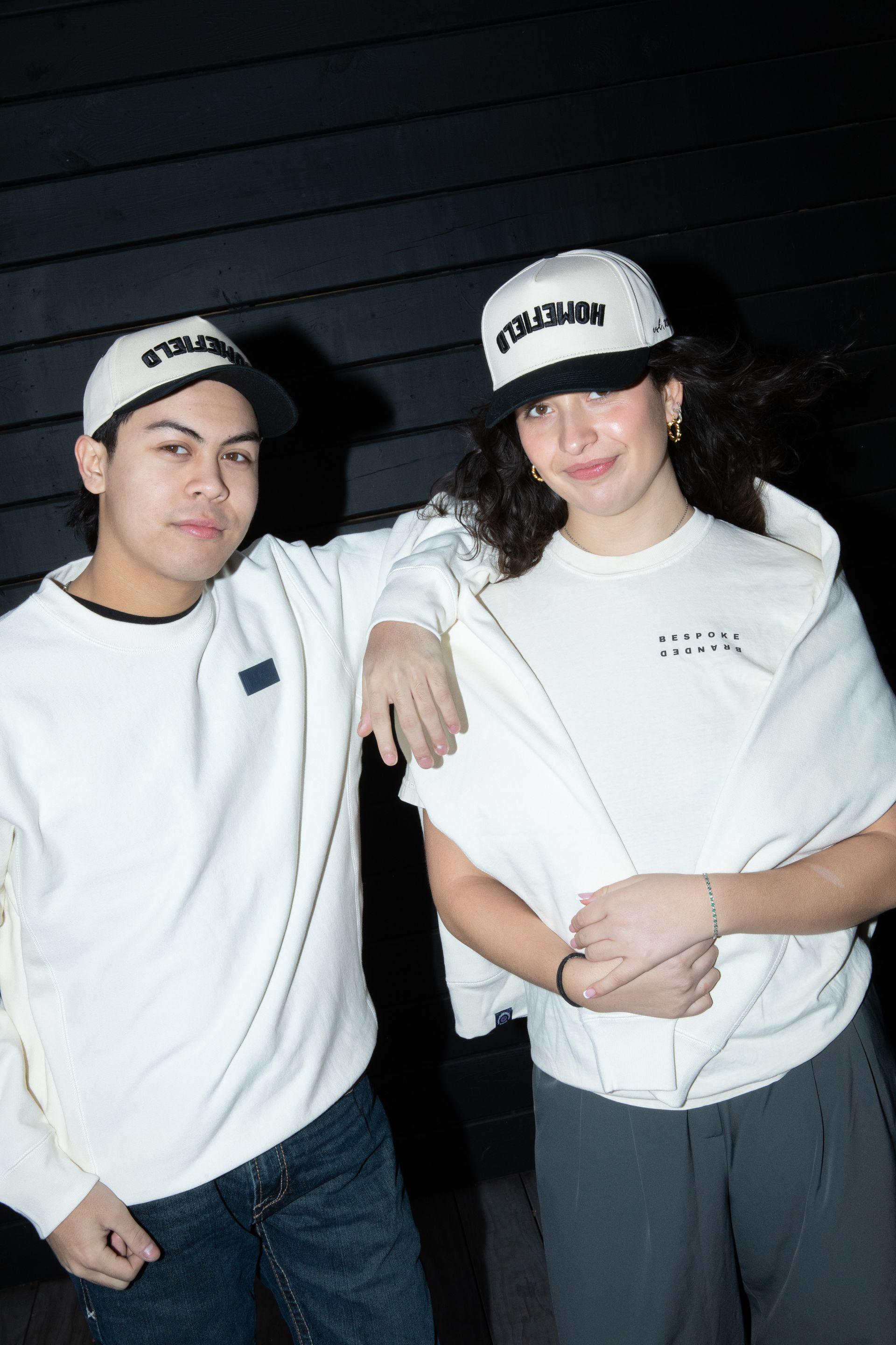 A man and a woman are standing next to each other wearing white shirts and hats.