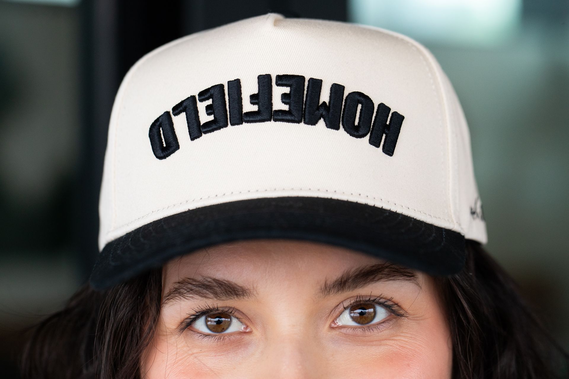 A woman wearing a white hat with the word homefield on it