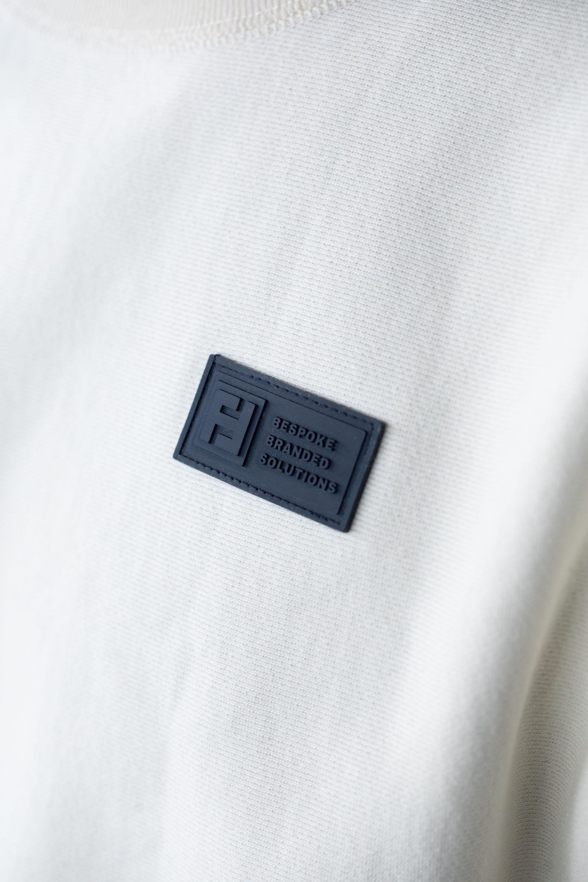 A close up of a white sweater with a blue label on it.