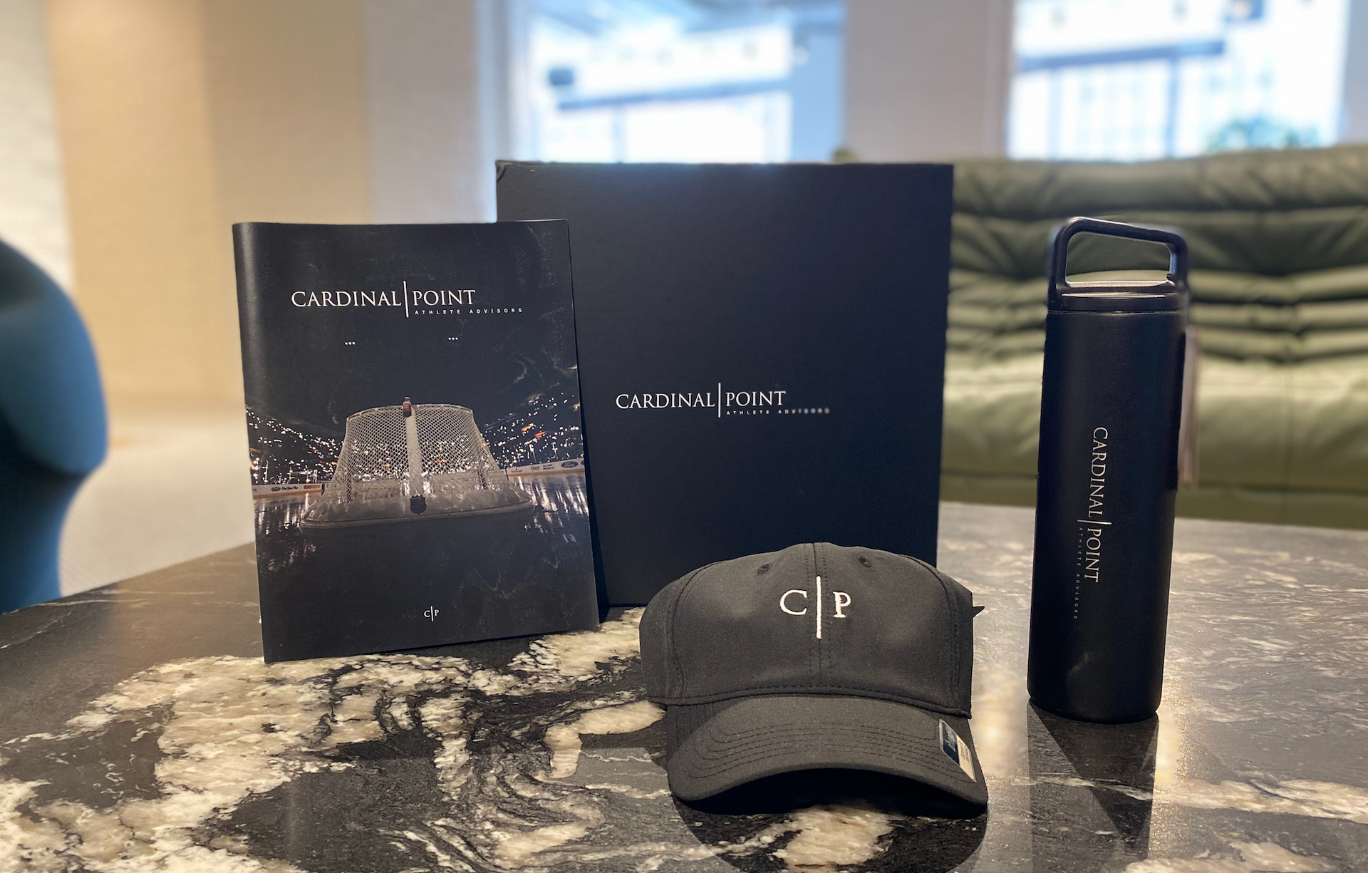 A table with a branded hat a book and a water bottle on it. 
