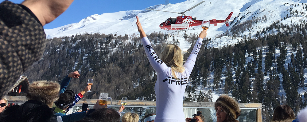 A woman is standing in front of a helicopter with her arms in the air.
