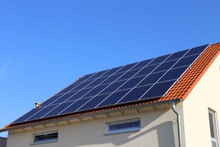 House roof covered with blue solar panels under a clear blue sky House roof covered with blue solar panels under a clear blue sky