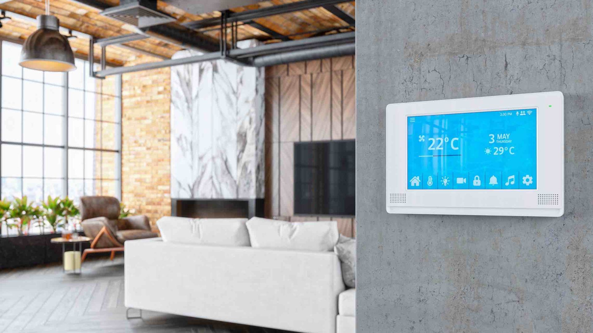Modern living room with a wall-mounted smart thermostat on a concrete wall and a white sofa nearby