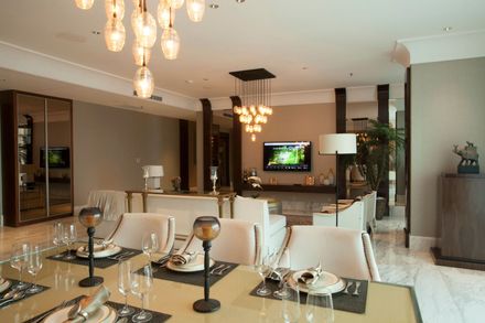 Empty white dining area with carpet, chandelier, and view into a kitchen and hardwood-floored room Empty white dining area with carpet, chandelier, and view into a kitchen and hardwood-floored room