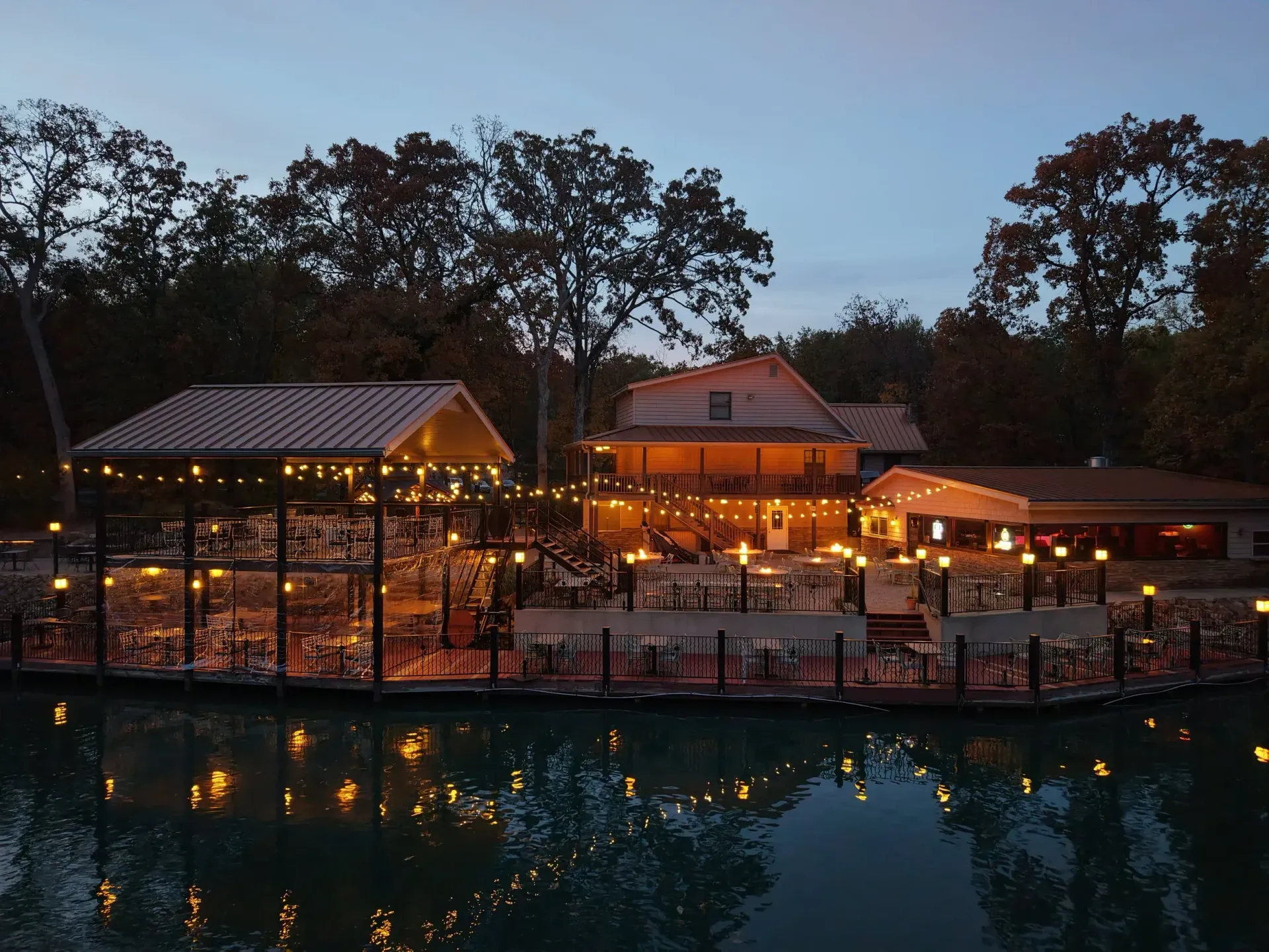 Pocahontas internet Lakeside restaurant at dusk with warm lights reflecting on calm water, surrounded by trees