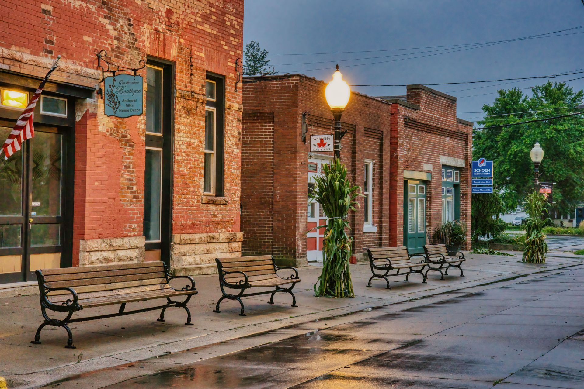 Brick-lined street with benches, lamp posts, and wet pavement in a quiet downtown scene
