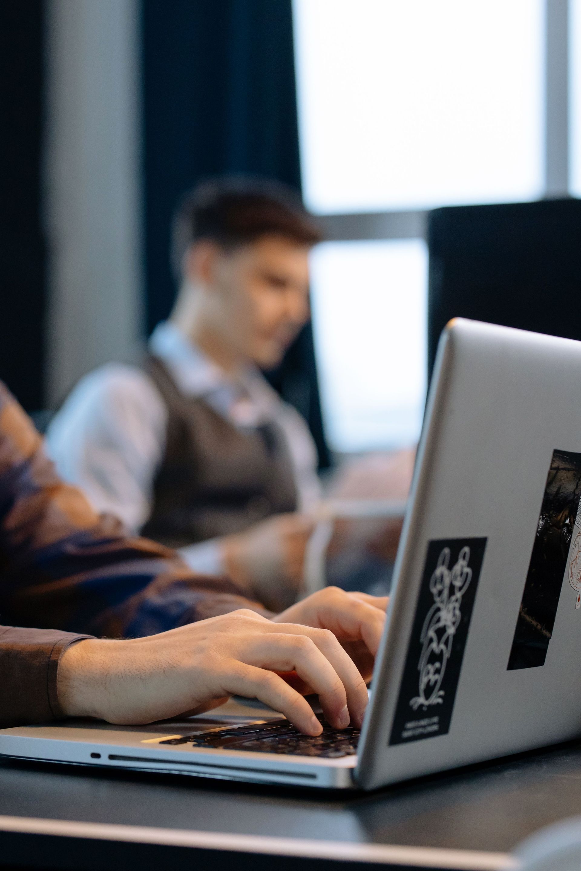 People typing on laptops in a classroom or office setting
