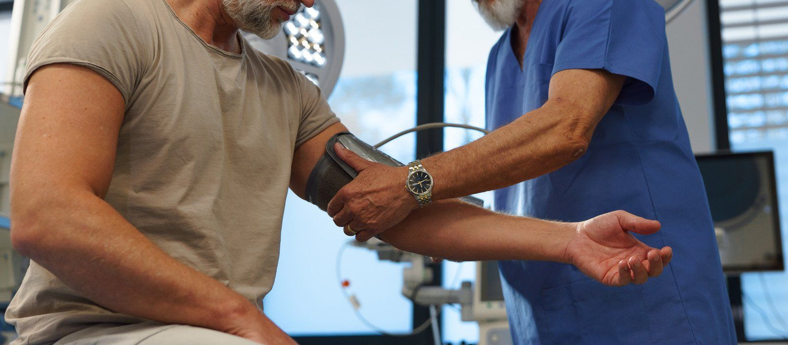A person's blood pressure is being checked by a health worker in a medical setting.