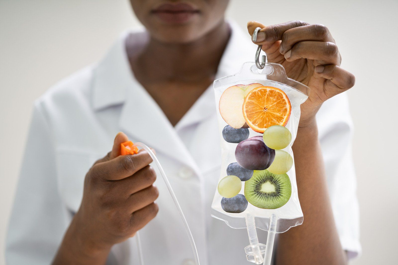 Nurse holding IV bag filled with fruit, likely for vitamin infusion.