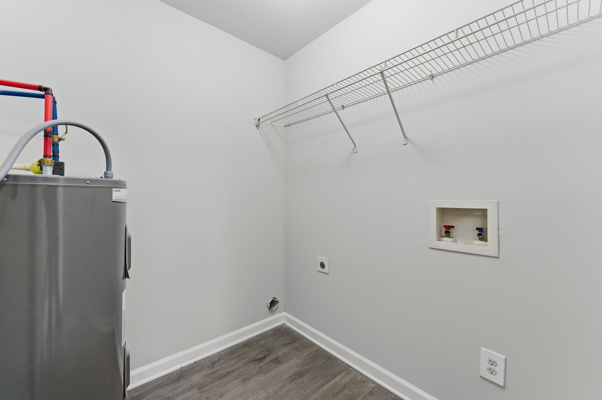 Laundry room with water heater, wall-mounted shelf, and washer/dryer hookups