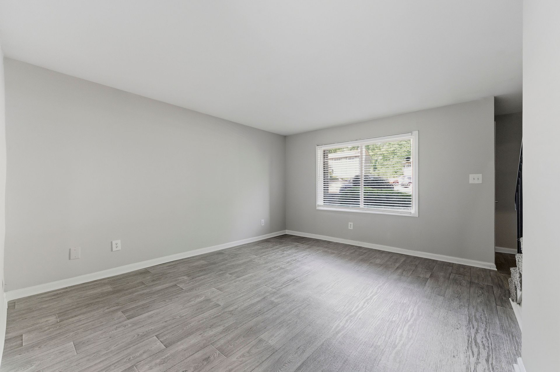 Empty gray bedroom with carpet, a window, and white trim.