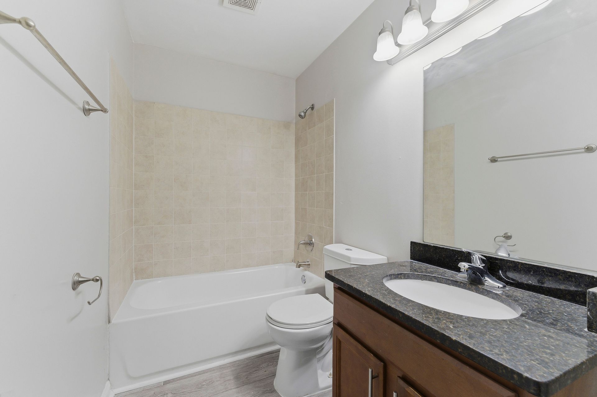 Bright bathroom with bathtub, toilet, and granite vanity with mirror