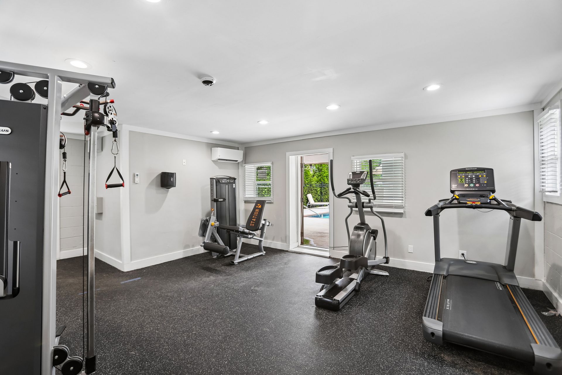 Modern home gym with treadmill, exercise bike, weight machine, and wall-mounted TV